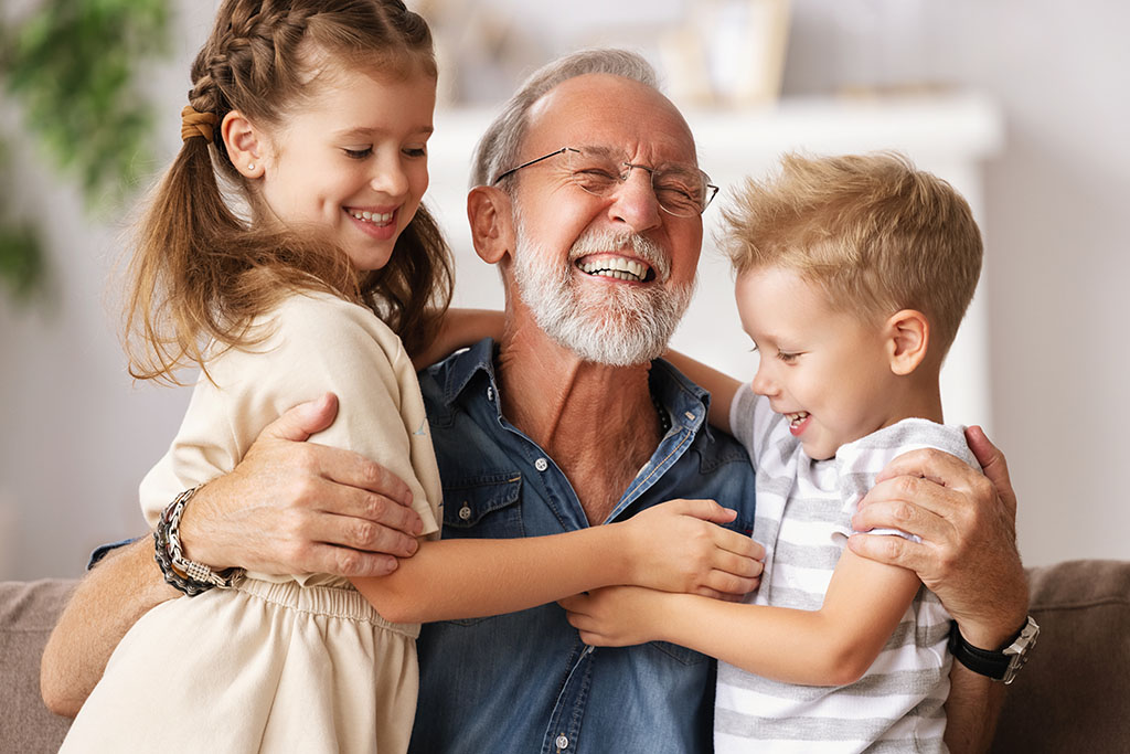 Grandfather hugging grandchildren on sofa