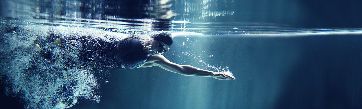 Athlete swimming freestyle on blue background, underwater view